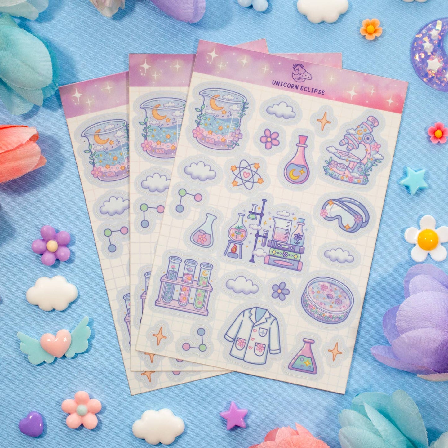 Sticker sheets with science-themed designs on a blue background with decorative elements.