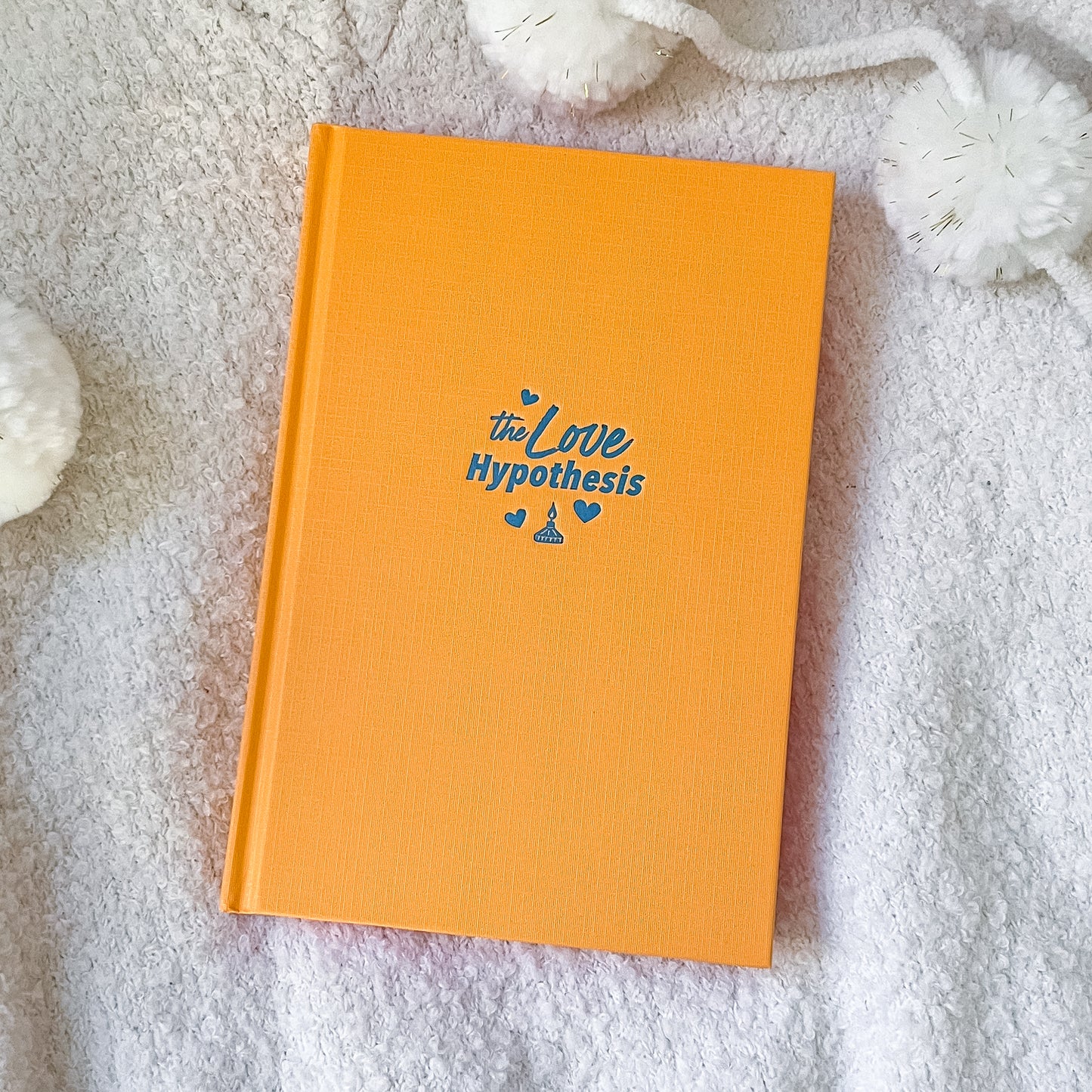 Orange book with 'the Love Hypothesis' text on a textured surface