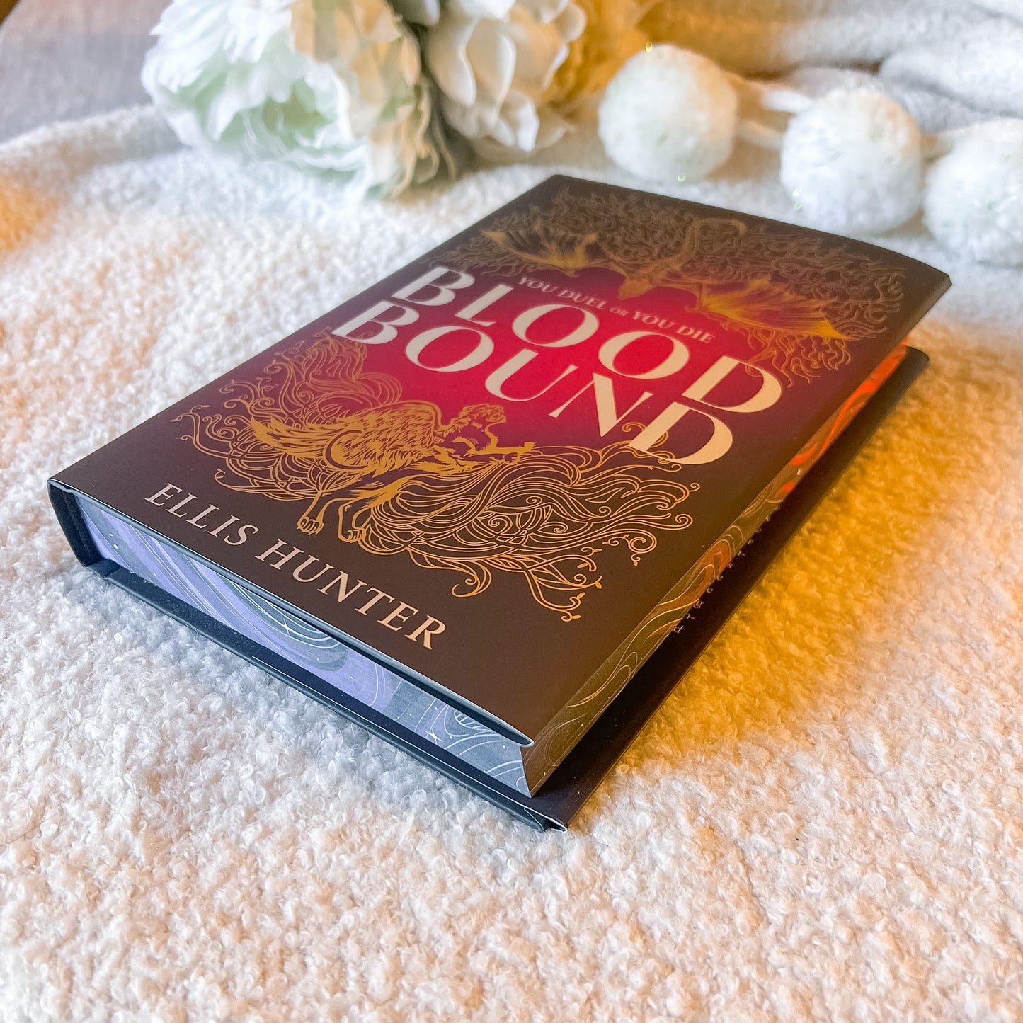 Book titled 'Blood Bound' by Ellis Hunter on a textured surface with decorative elements.