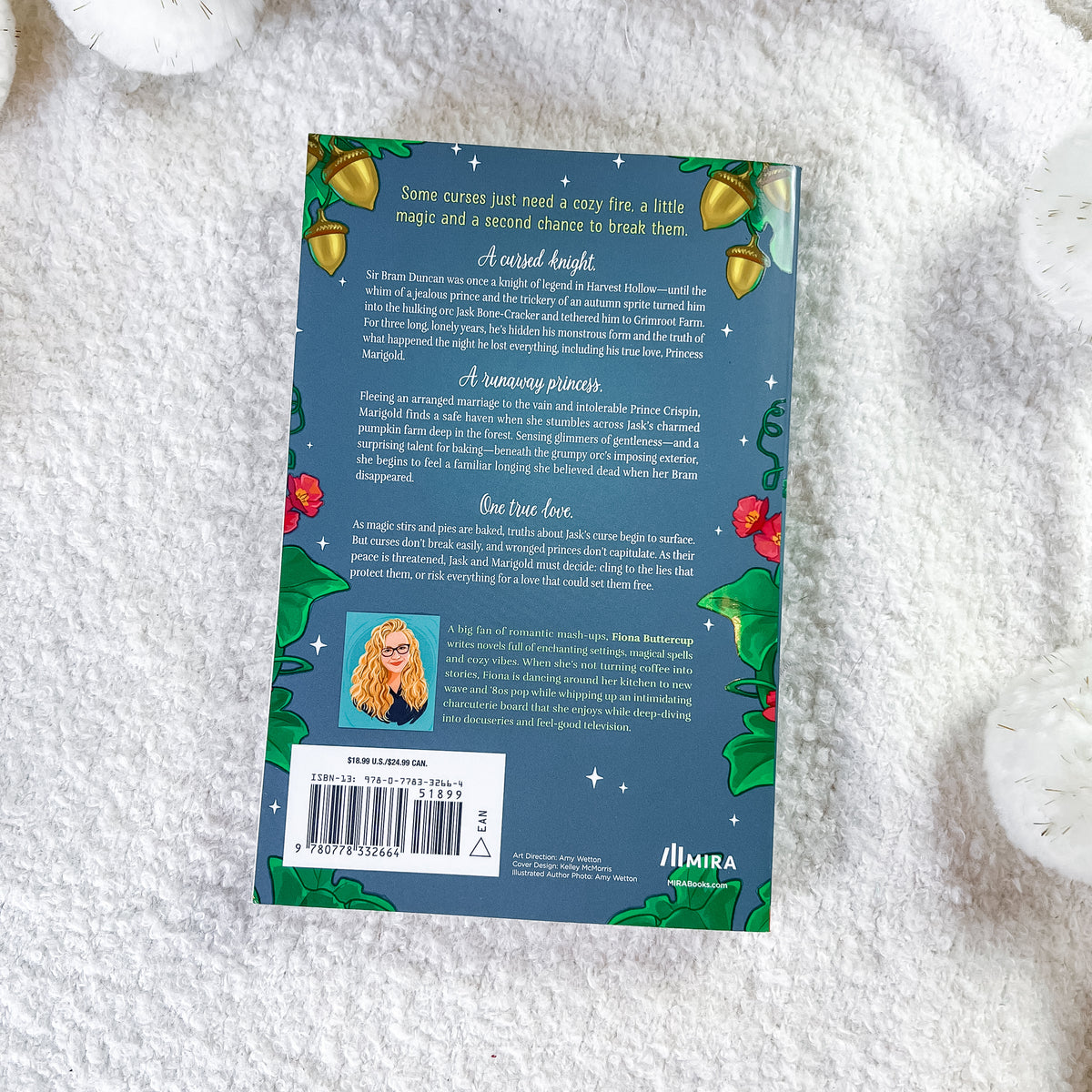 The back cover of the book, styled flat on a white textured fabric background. The cover features a dark teal background decorated with green holly leaves, red berries, gold bells, and white stars, with a small portrait of a woman in a red dress and a barcode at the bottom left.