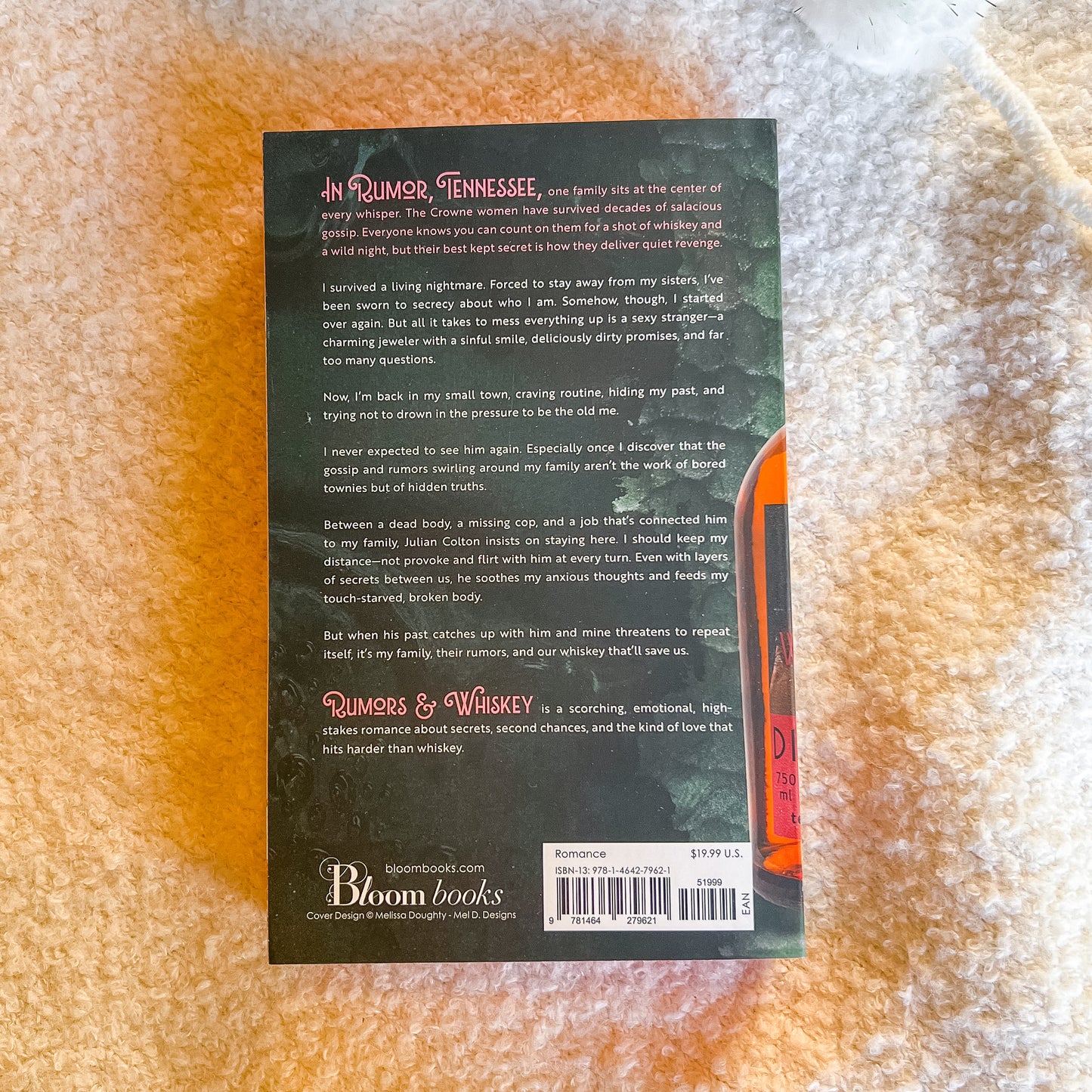 Back cover of a book titled 'Rumors & Whiskey' by Bloom Books on a textured surface.