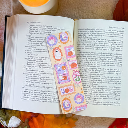 A handmade paper bookmark featuring cartoon ghosts and the attached to the right page.