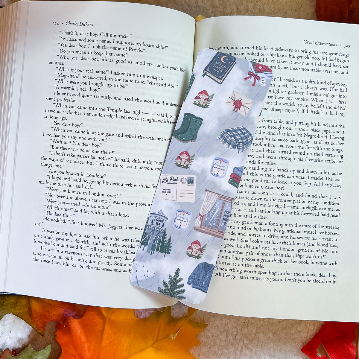 An open book spread showing printed text and a collage of small vintage-style illustrations, photographed on a wooden surface with a yellow patterned cloth underneath part of the pages.