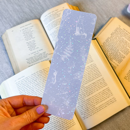 Hand holding a decorative bookmark over open books on a textured surface