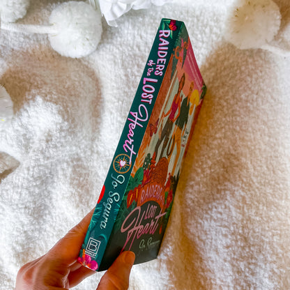 Hand holding a 'Raider of the Lost Ark' book with a colorful cover against a textured white background