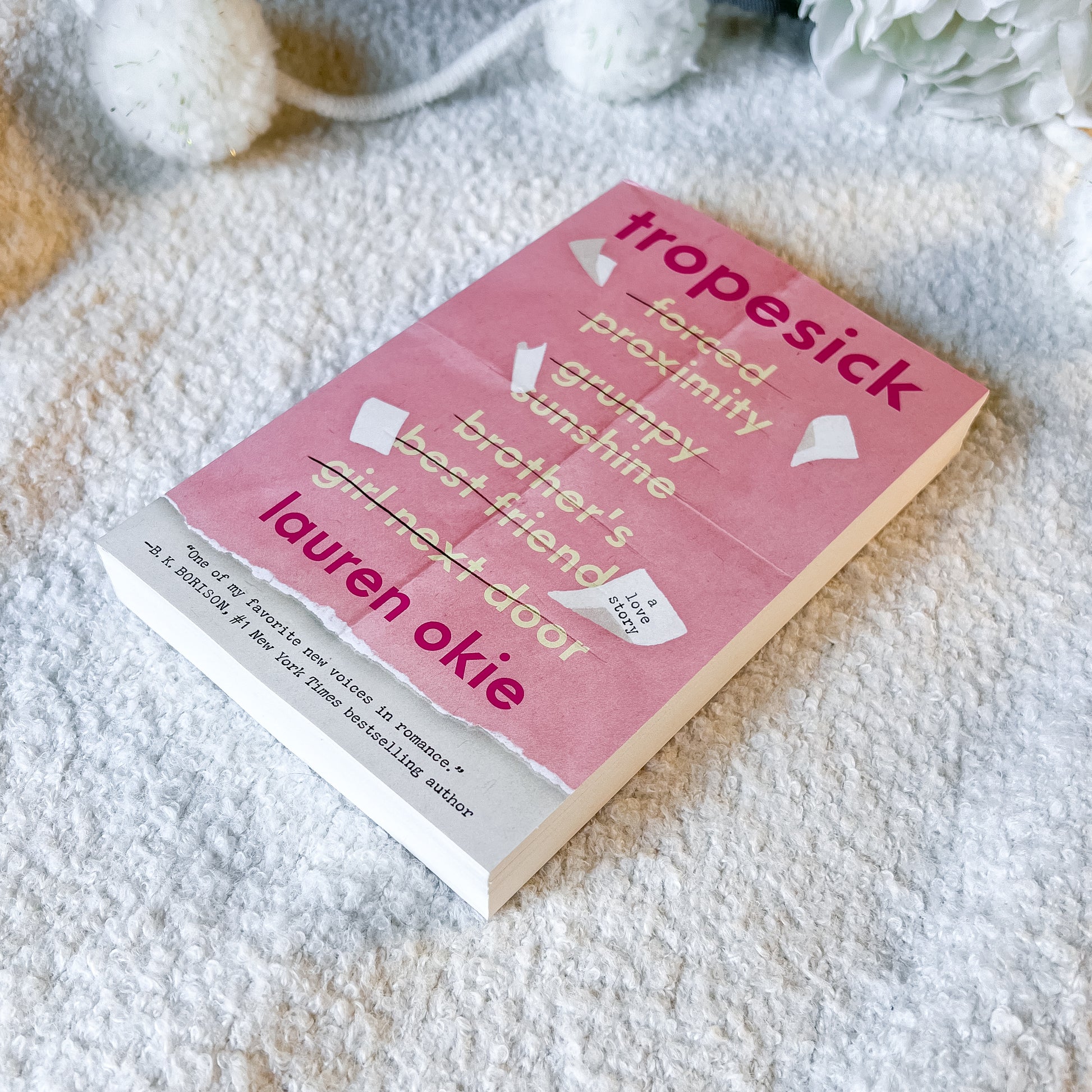 Book titled 'tropesick' by Lauren Okie on a textured surface with decorative elements.