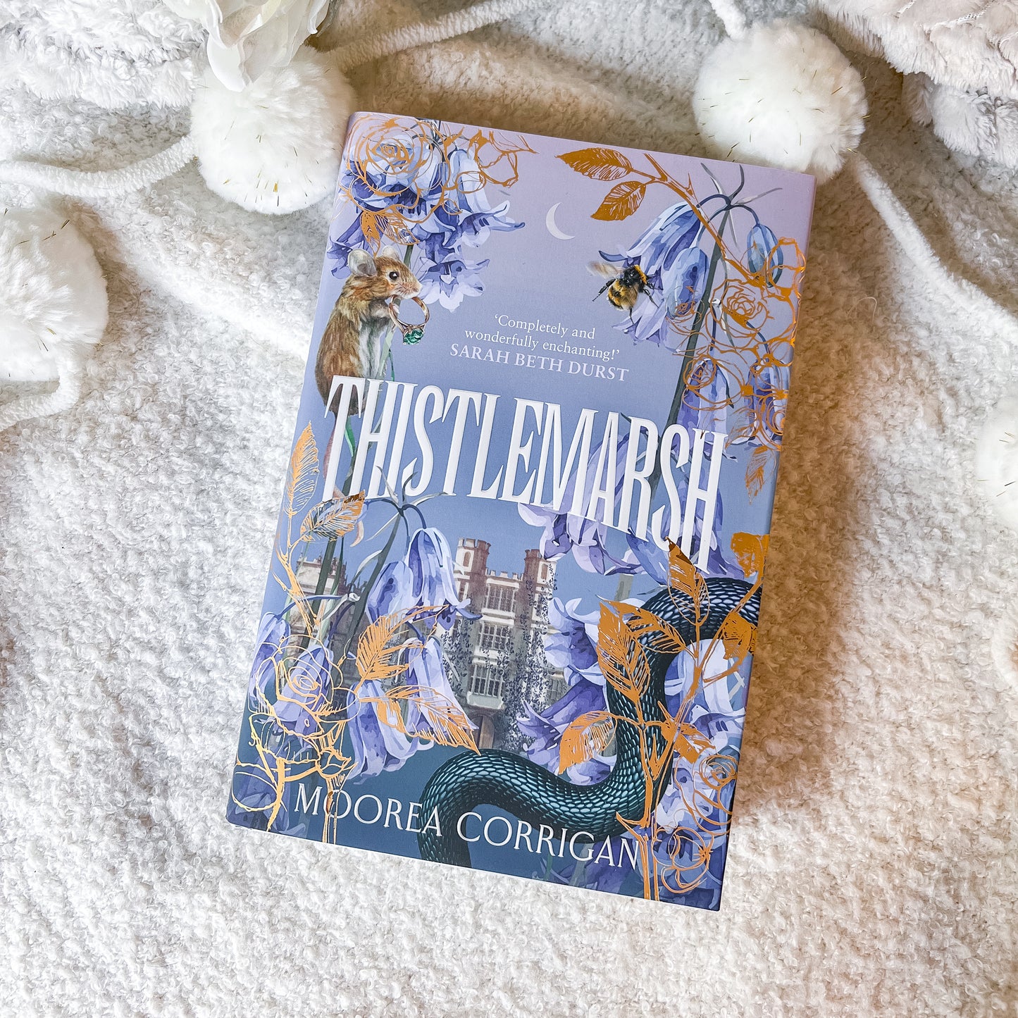 Book titled 'Thistlemarsh' by Moorea Corrigan on a soft, white surface.