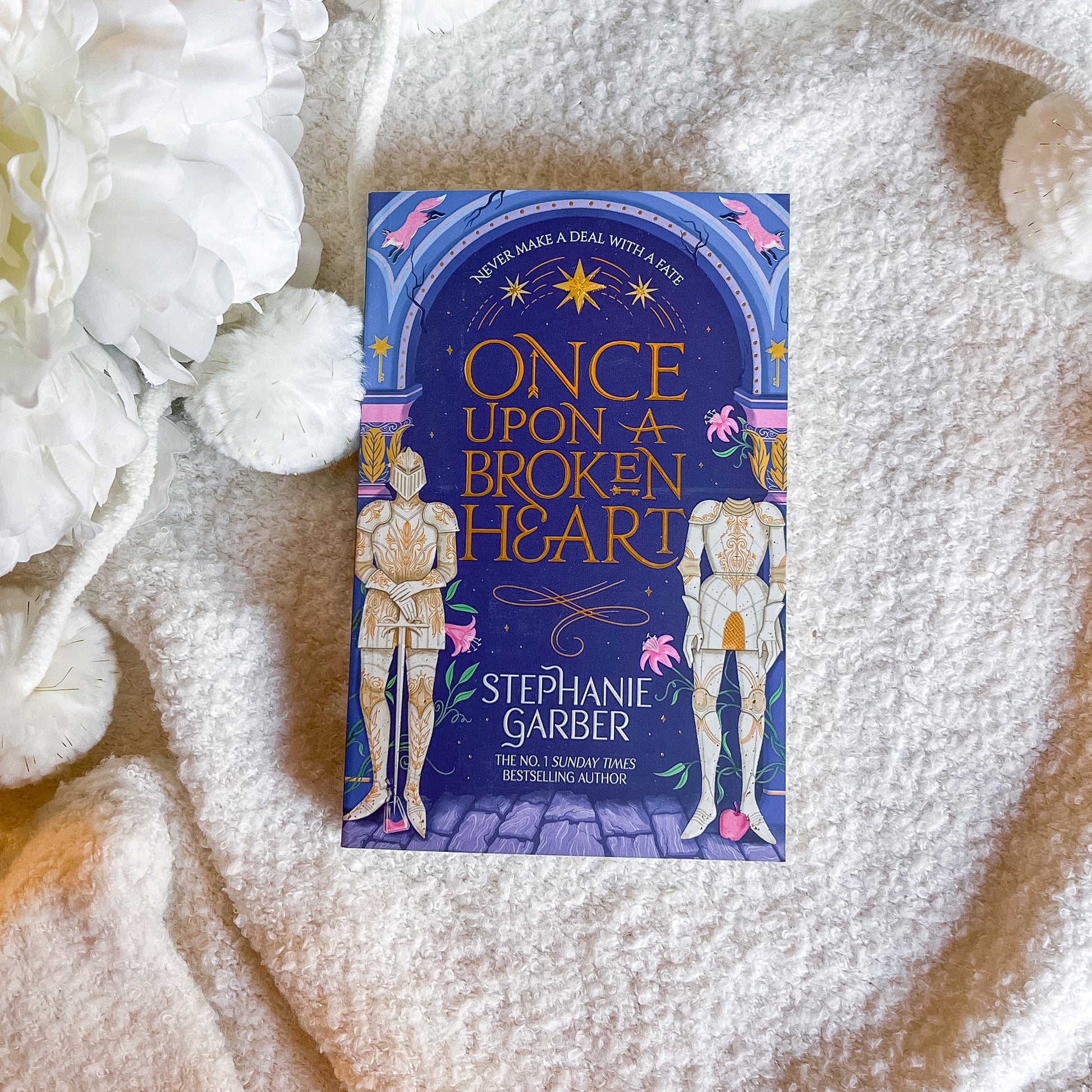 Book titled 'Once Upon a Broken Heart' by Stephanie Garber on a textured surface with white flowers.