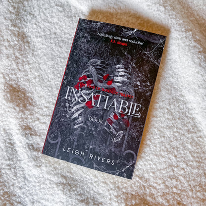 Book titled 'Insatiable' by Leigh Rivers on a textured surface