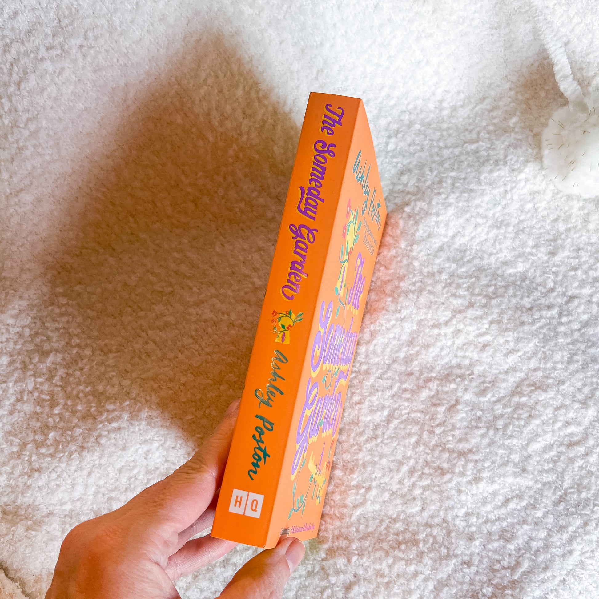Hand holding an orange box with colorful text and graphics on a textured white background