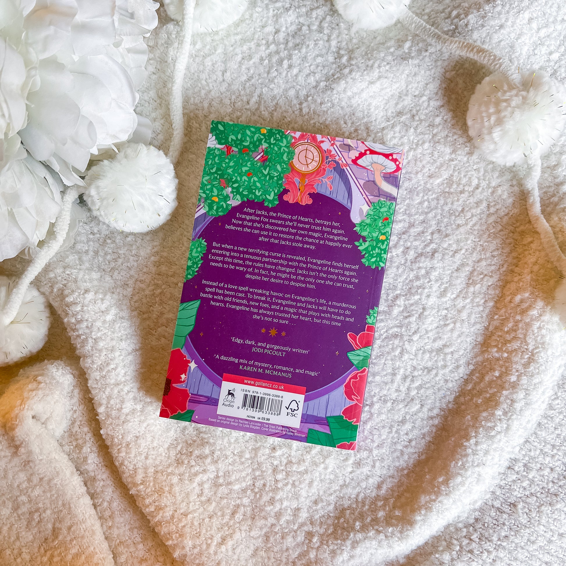 Book with colorful back cover on a textured surface with white flowers