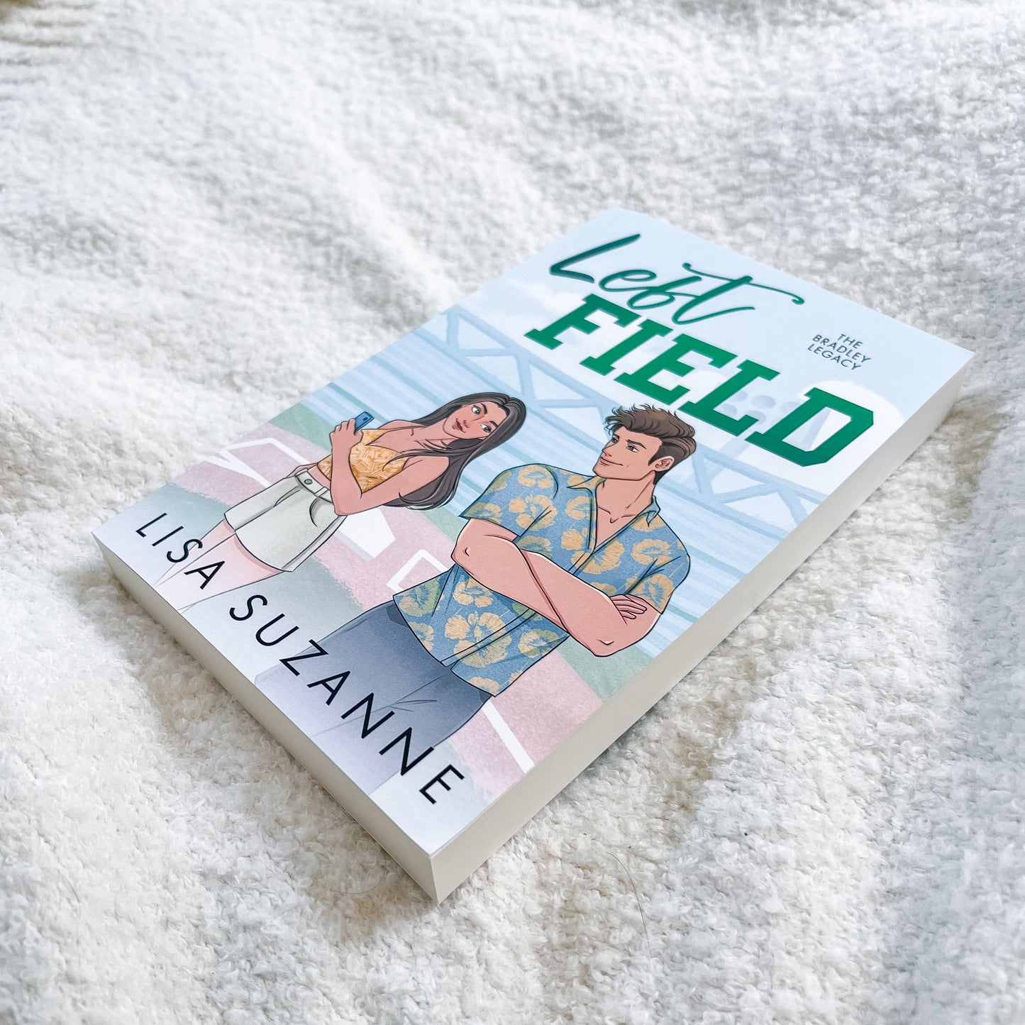 Book titled 'Left Field' by Lisa Suzanne on a textured white surface