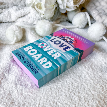 Book titled 'Love Over Board' by Kandi Steiner on a textured surface with decorative elements.