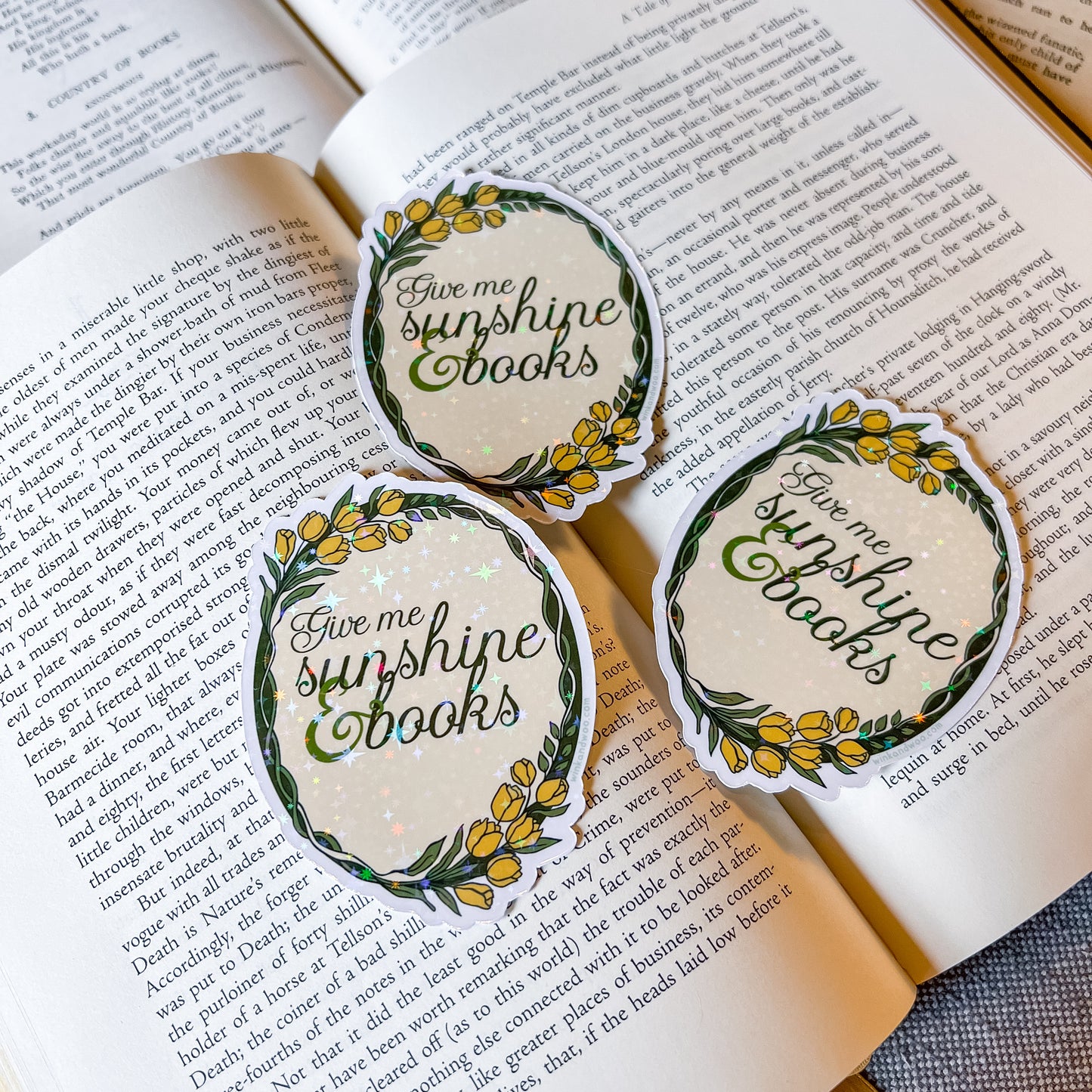 Three 'Give me sunshine books' stickers on an open book