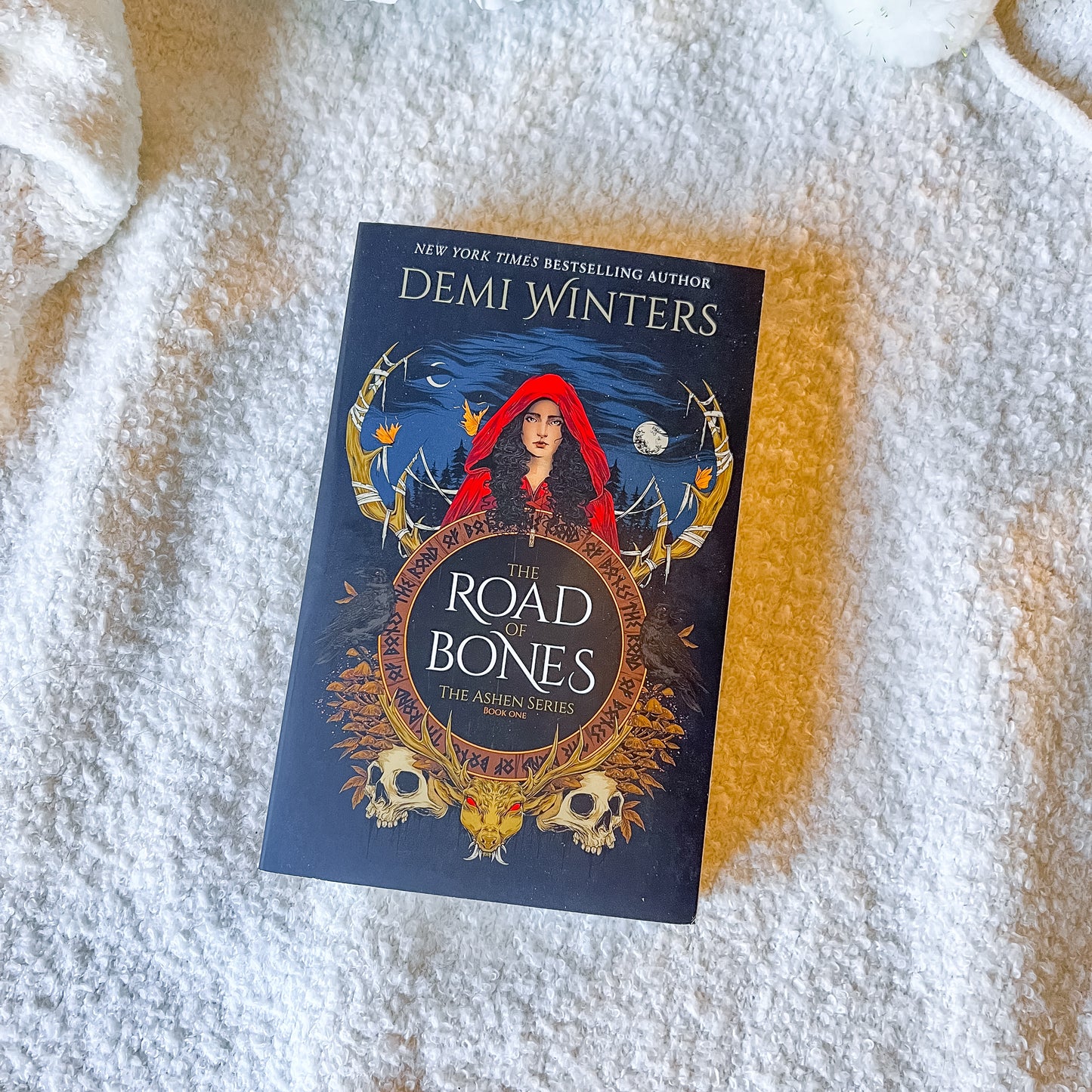 Book titled 'The Road of Bones' by Demi Winters on a textured surface