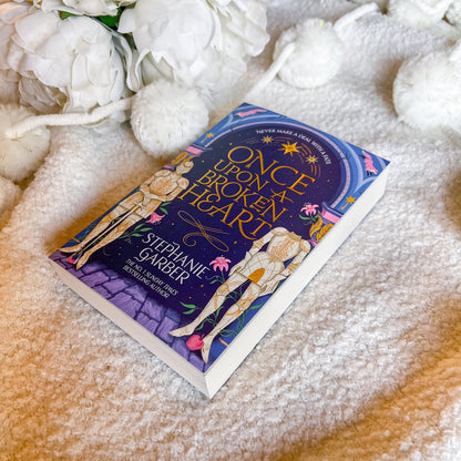 Book titled 'Once Upon a Broken Heart' by Stephanie Garber on a soft surface with flowers.