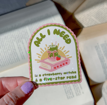 Sticker with text 'All I Need is a Strawberry Matcha & a Five-Star Read' held by a hand.