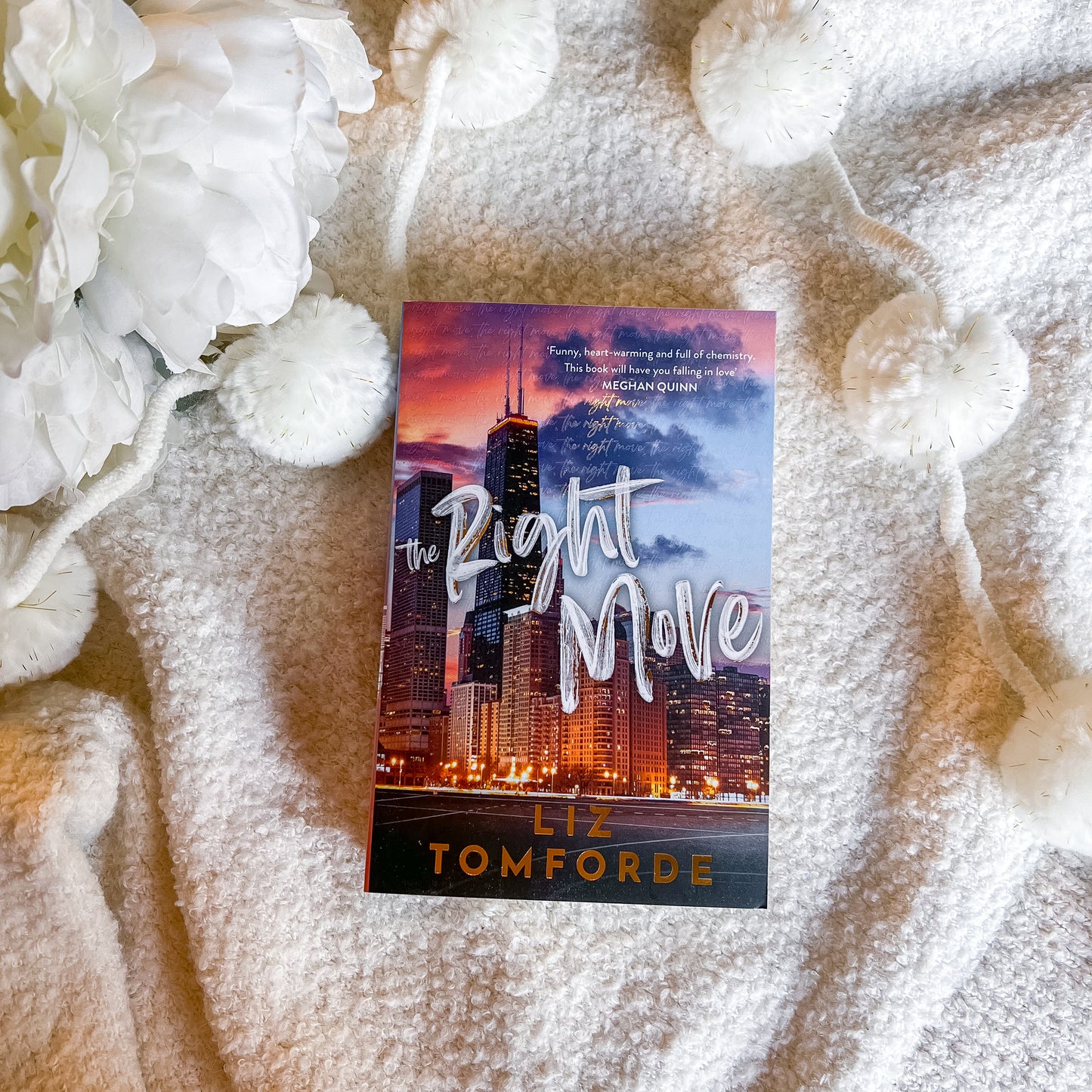 Book titled 'The Right Move' by Liz Tomforde on a textured surface with white flowers.