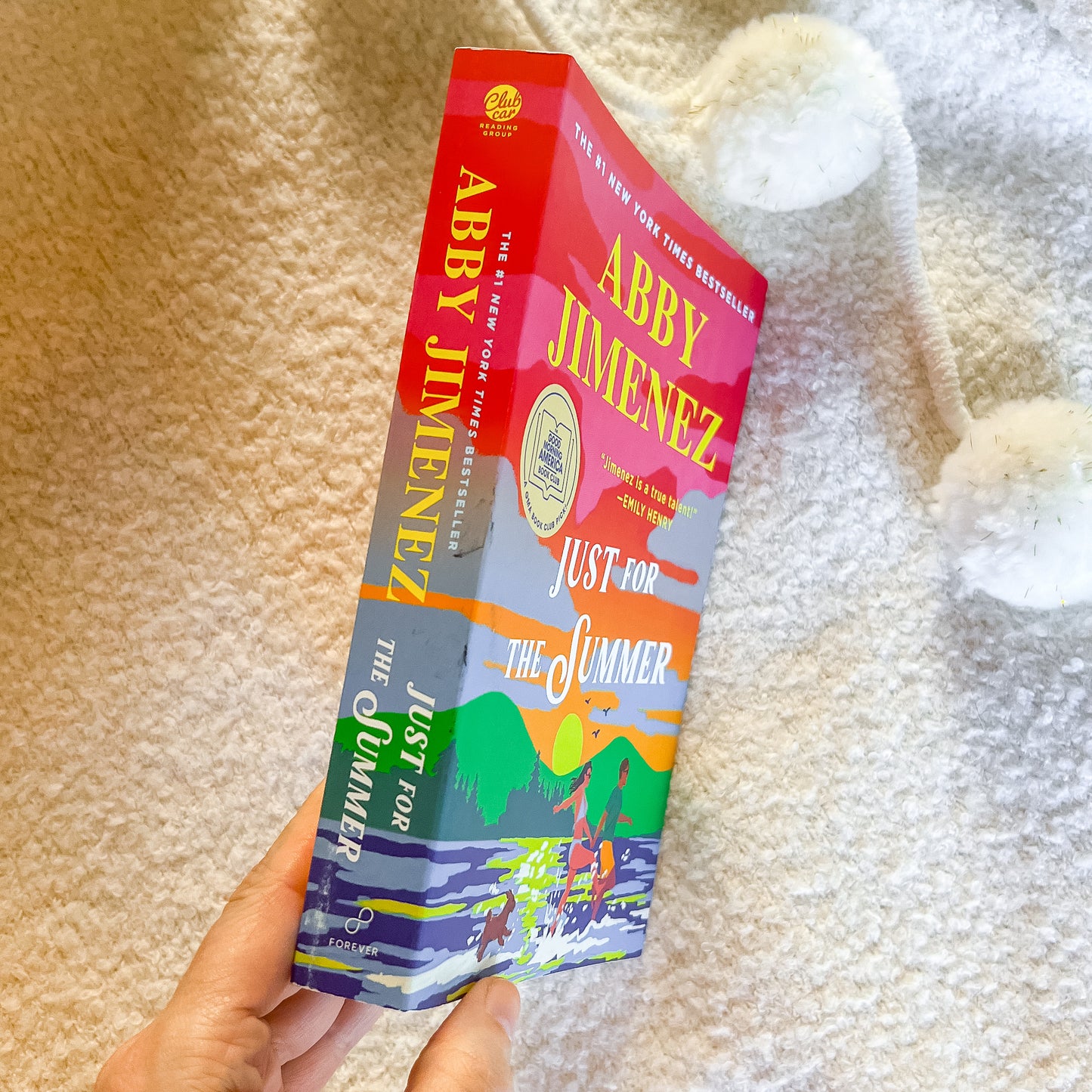 Book titled 'Just for the Summer' by Abby Jimenez held against a textured beige background