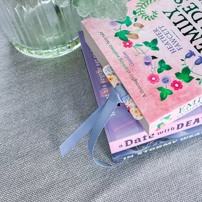 Floral bookmark with a blue ribbon tucked into a book.