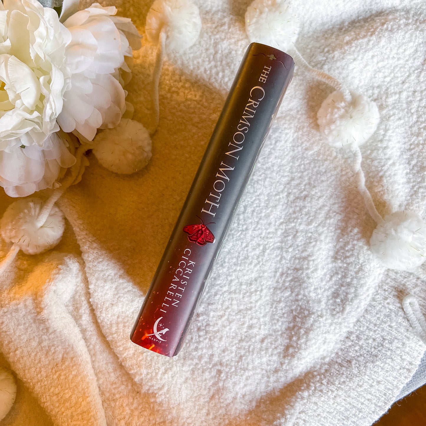 Spine of "The Crimson Moth" with floral and textured fabric background
