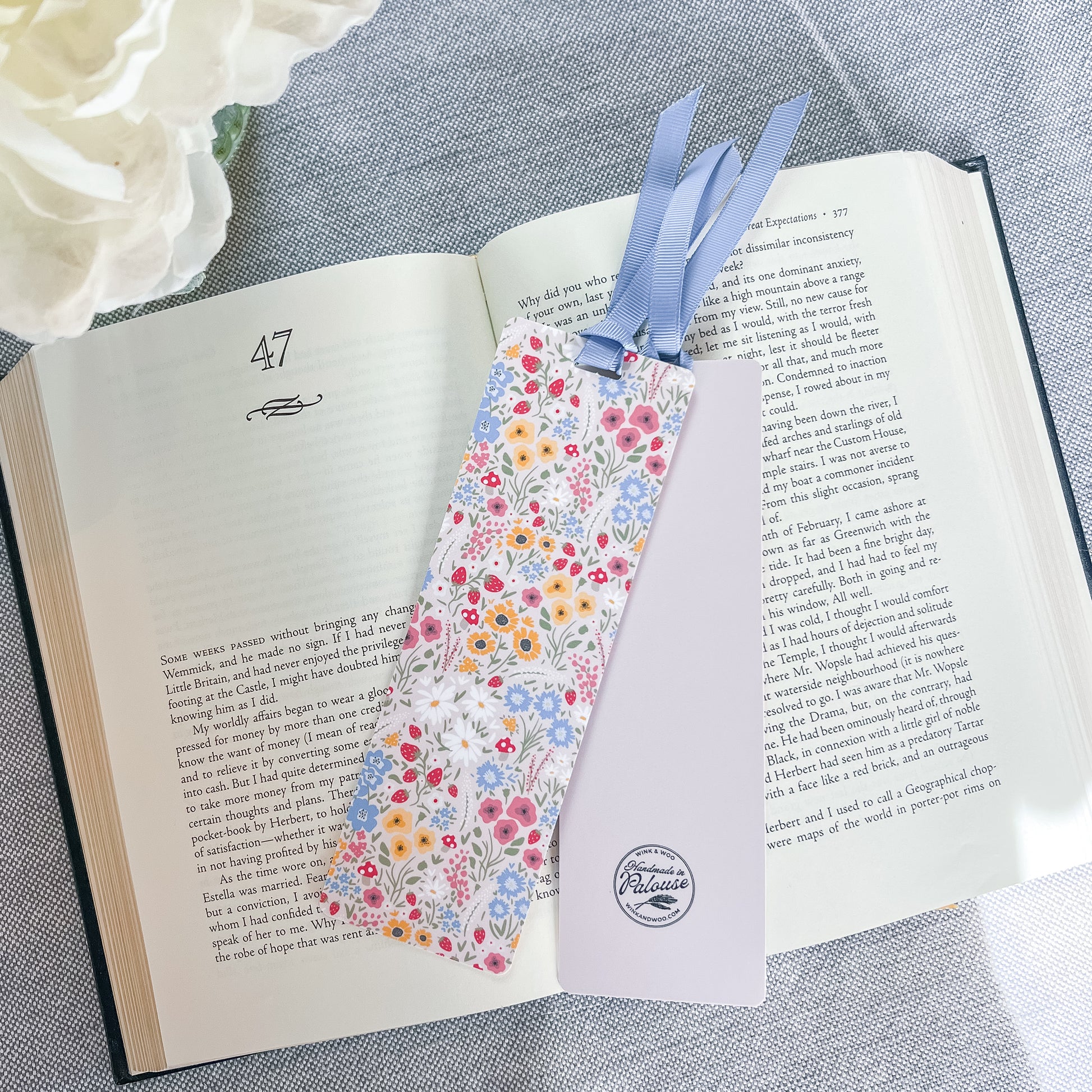 Floral bookmark with a blue ribbon sitting on top of a book