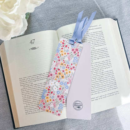 Floral bookmark with a blue ribbon sitting on top of a book