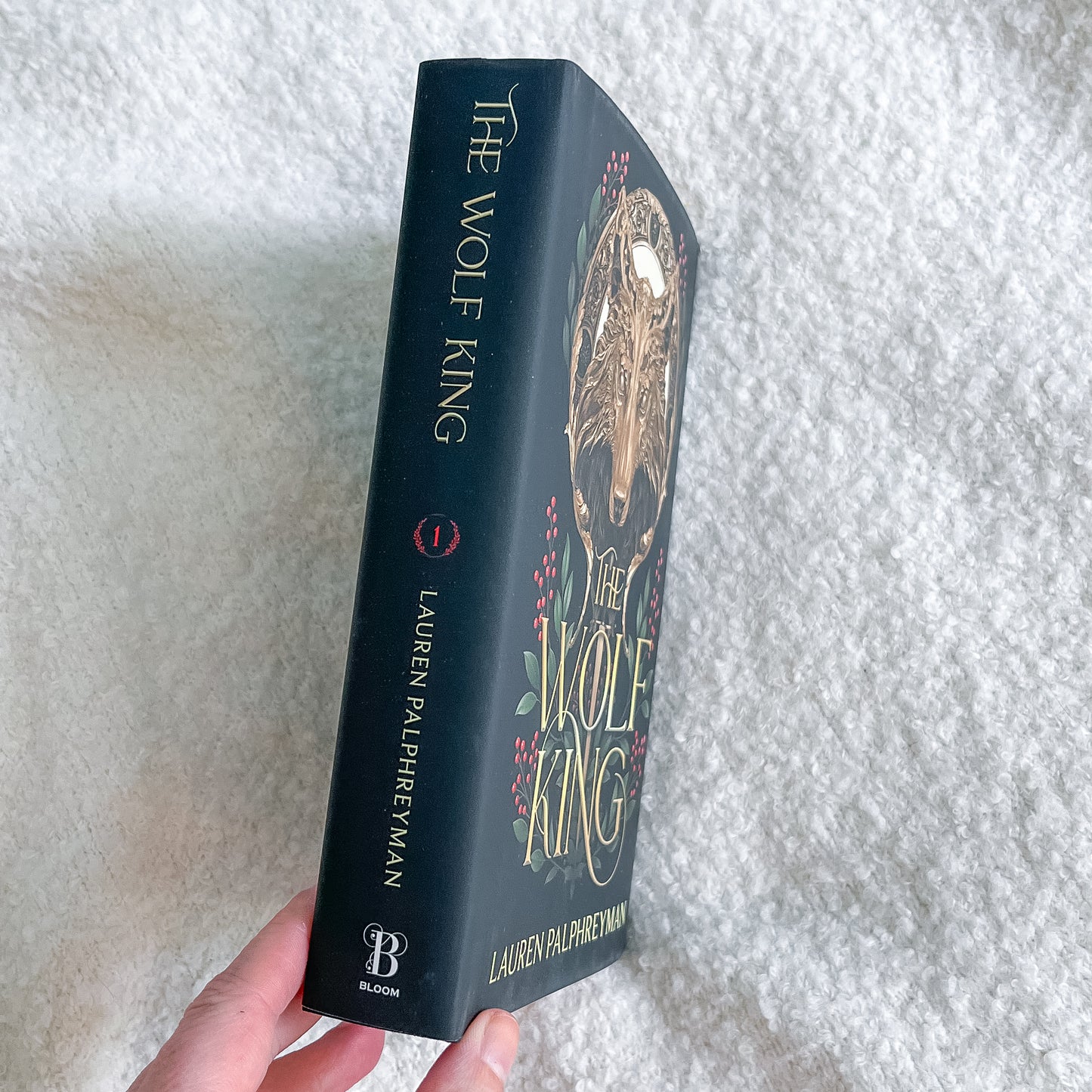 Book titled 'The Wolf King' by Lauren Palphreyman held against a textured white background