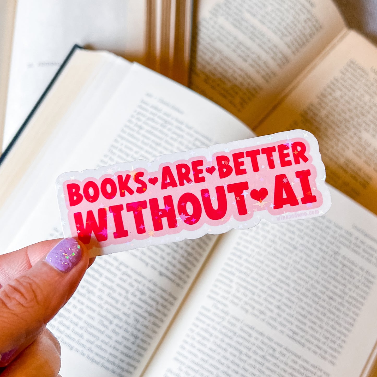 Sticker with 'Books are better without AI' text held over an open book