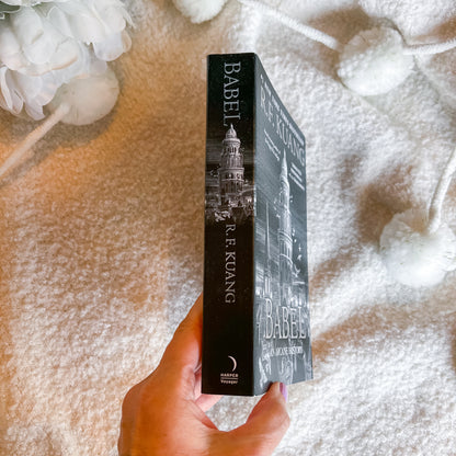 A hand holds a copy of the book 'Babel' by R. F.