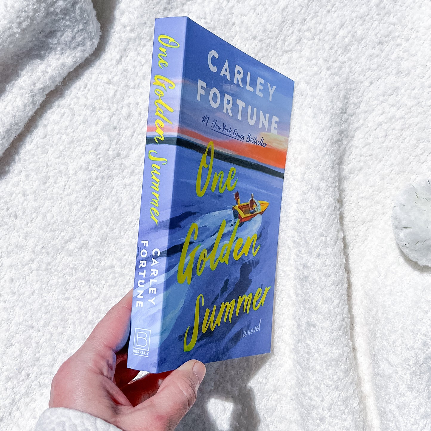 Book titled 'One Golden Summer' by Carley Fortune held against a textured white background