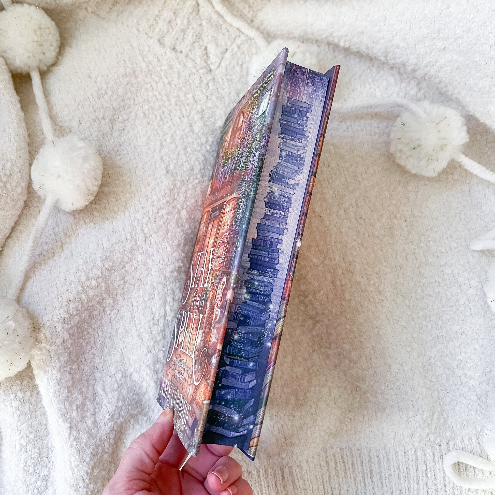 Hand holding a colorful book against a soft, textured white background
