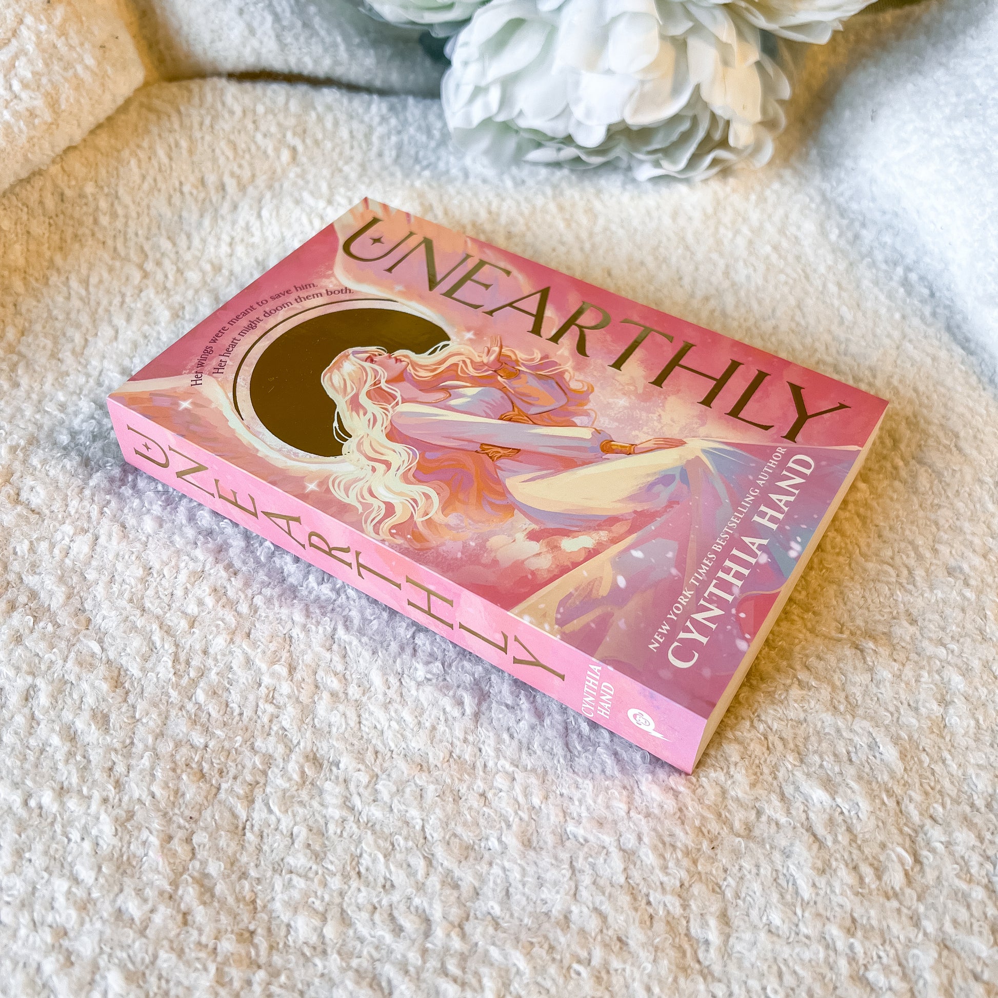 Book titled 'Unearthly' by Cynthia Hand on a textured surface with decorative elements.