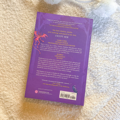 Purple book cover with text and a red spider illustration on a textured beige surface