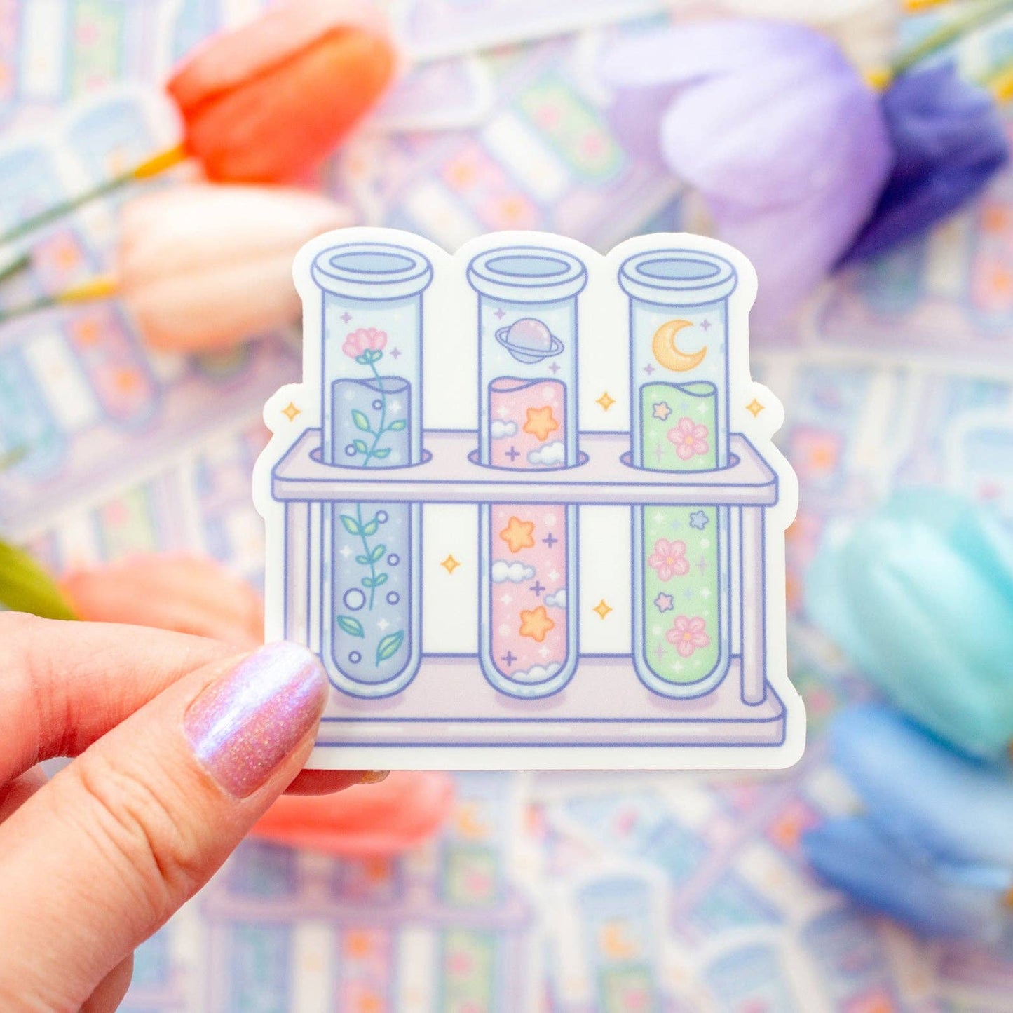 Sticker of test tubes with floral designs held by a hand against a colorful blurred background