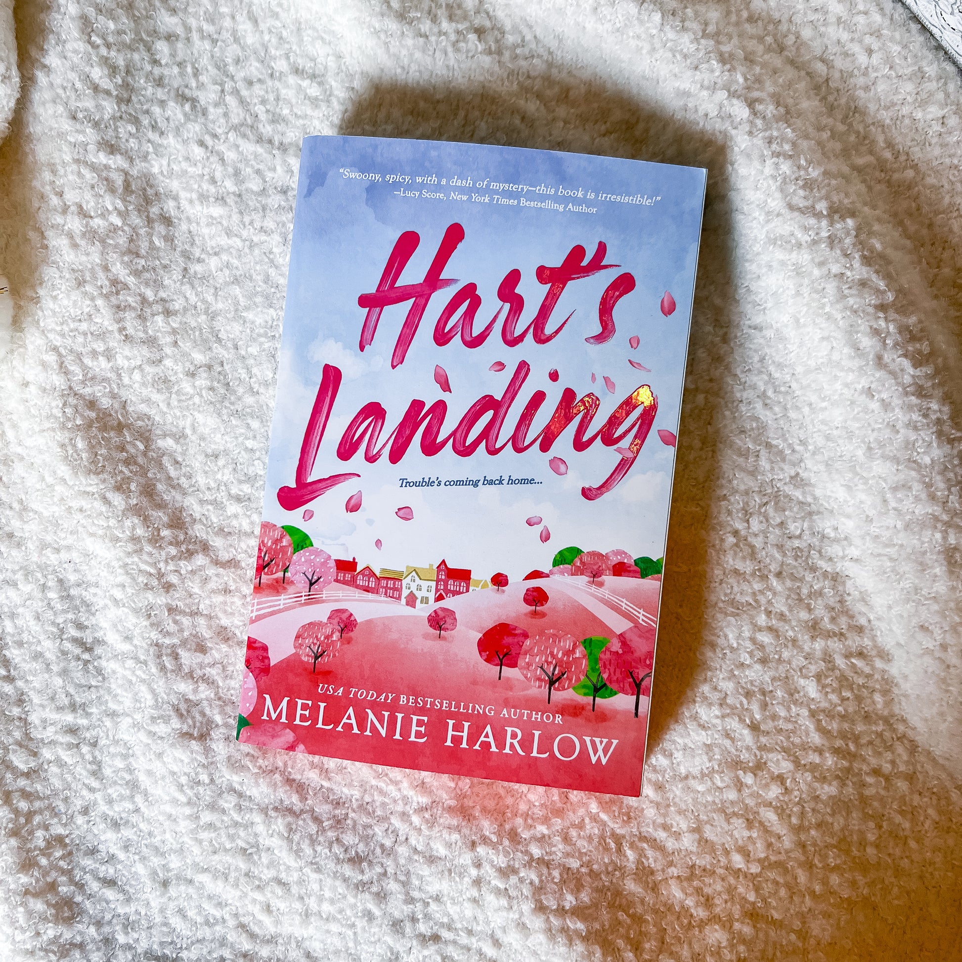 Book titled 'Hart's Landing' by Melanie Harlow on a textured surface