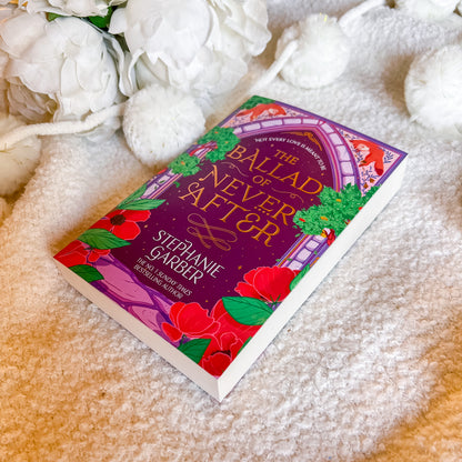 Book titled 'The Ballad of never After' by Stephanie Garber on a soft surface with flowers.