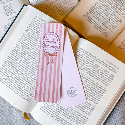 Pink striped bookmark with 'Feelin' Fancy' design on an open book