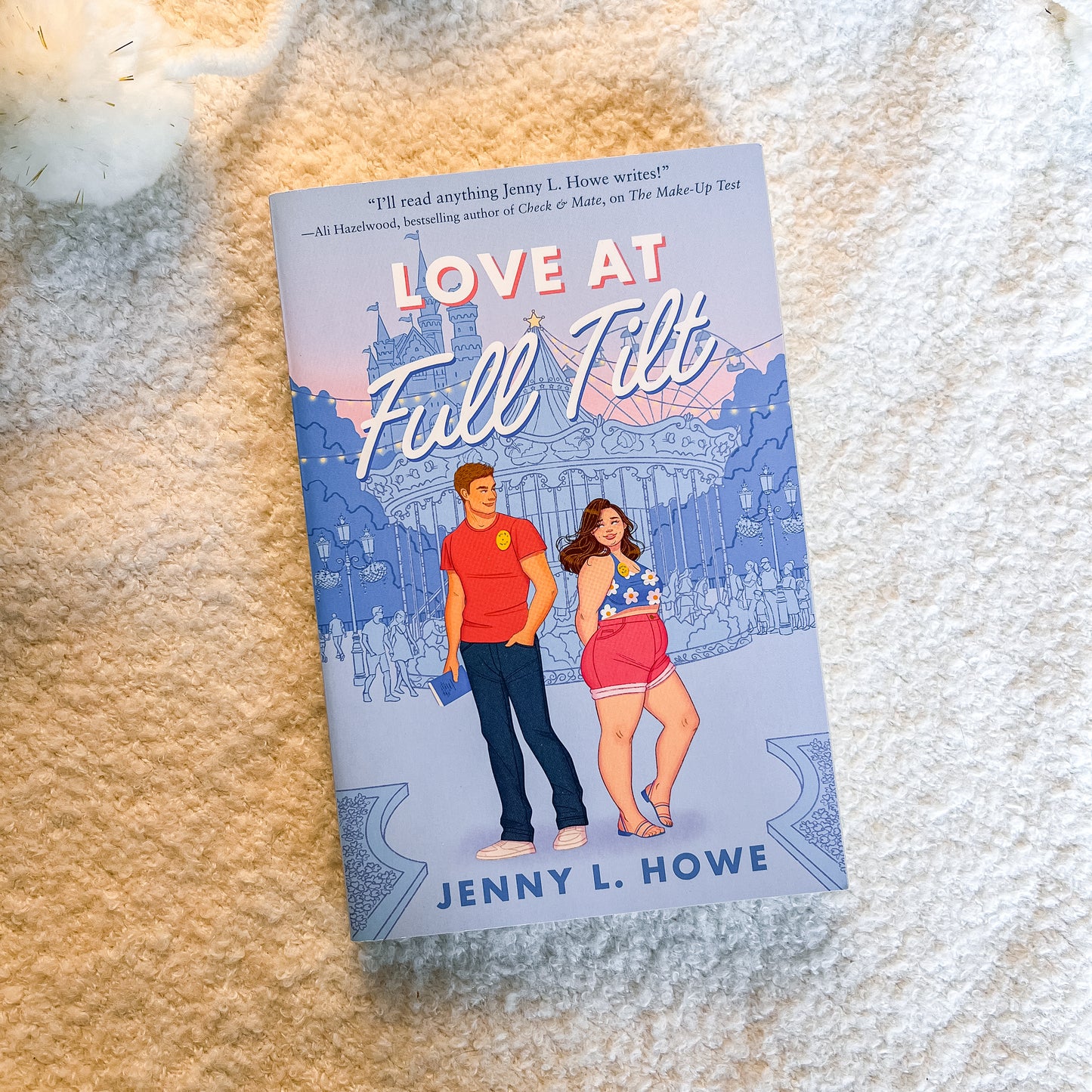 The book cover of 'Love At Full Tilt' by Jenny L. Howe is shown flat on a textured cream-colored blanket.