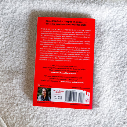 The back cover of the book 'The End or the End Again' by Katie Cahill, featuring a bright red background with black text, a barcode, and a small author photo, photographed flat on a textured gray fabric background.