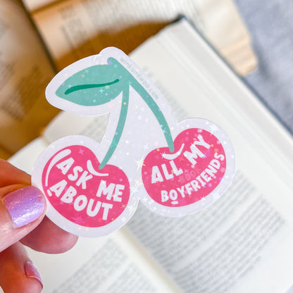 Two cherry-shaped stickers with text held by a hand on a blurred background