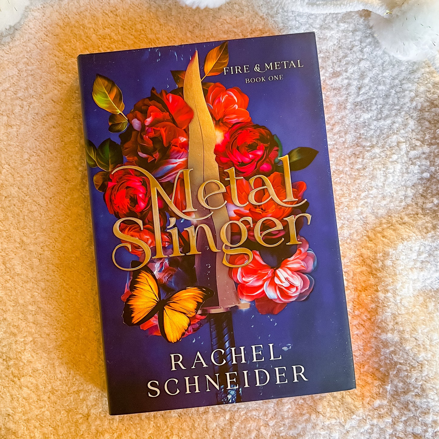 Book titled 'Metal Slinger' by Rachel Schneider on a textured surface