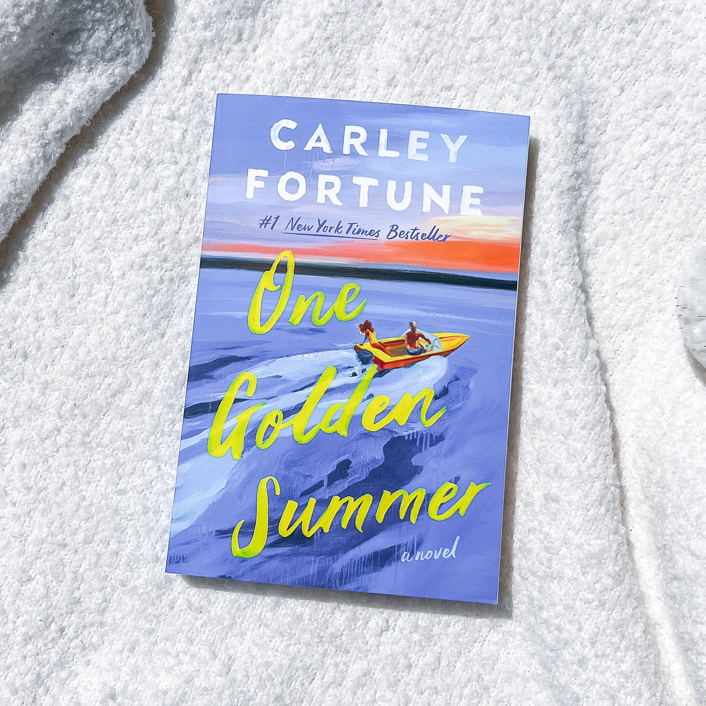 Book cover of 'One Golden Summer' by Carley Fortune on a textured white surface
