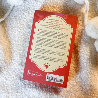 The back cover of a book by Bloom Books, featuring a red border and a cream-colored text block, laid flat on a white textured blanket.