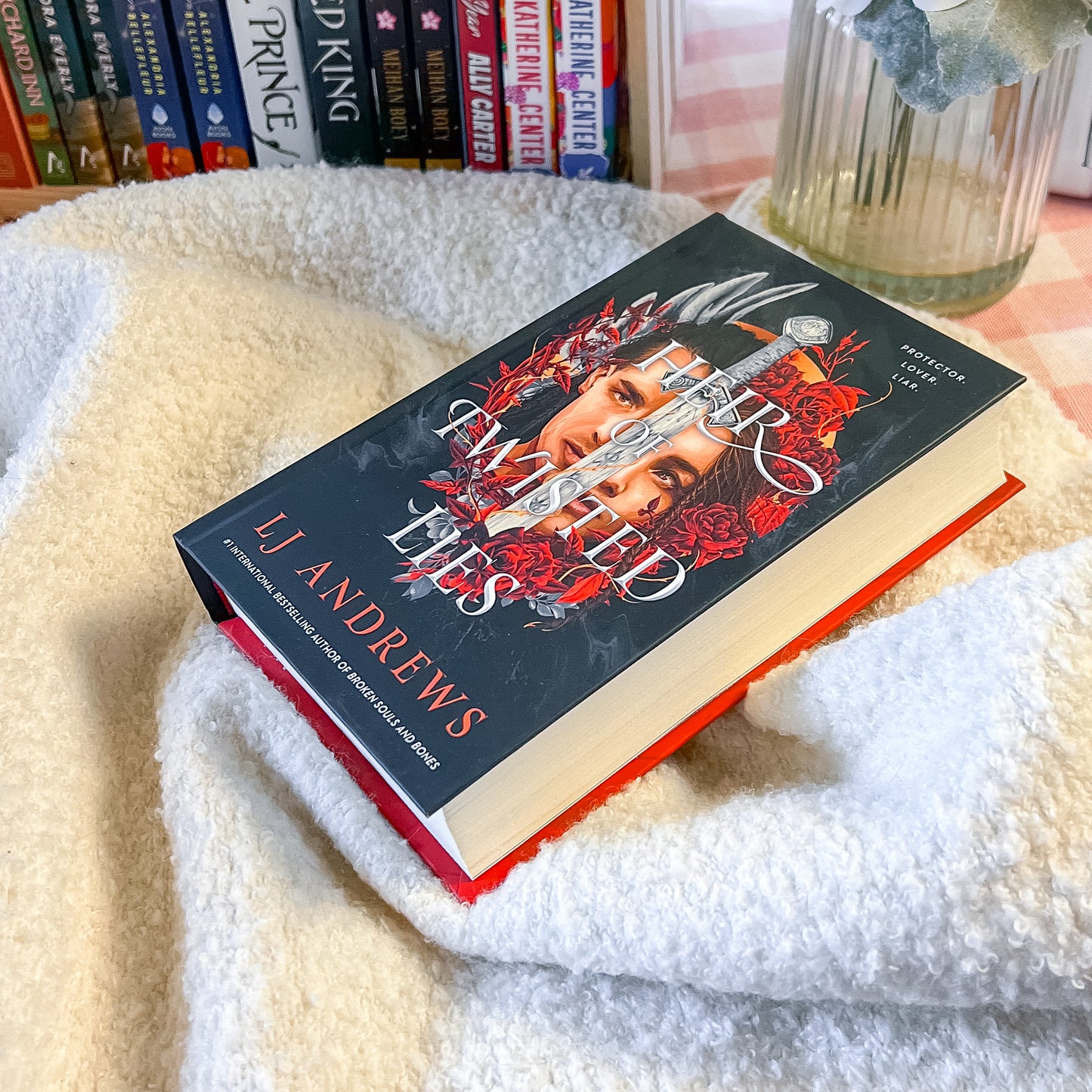Book by L.J. Andrews on a white blanket with books in the background