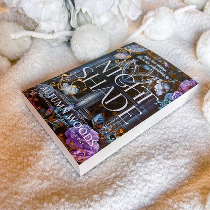 Book titled Nightshade by Autumn Woods on a textured surface with flowers.