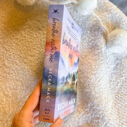 Book titled 'Breathe with Me' by Becka Mack held against a textured beige background