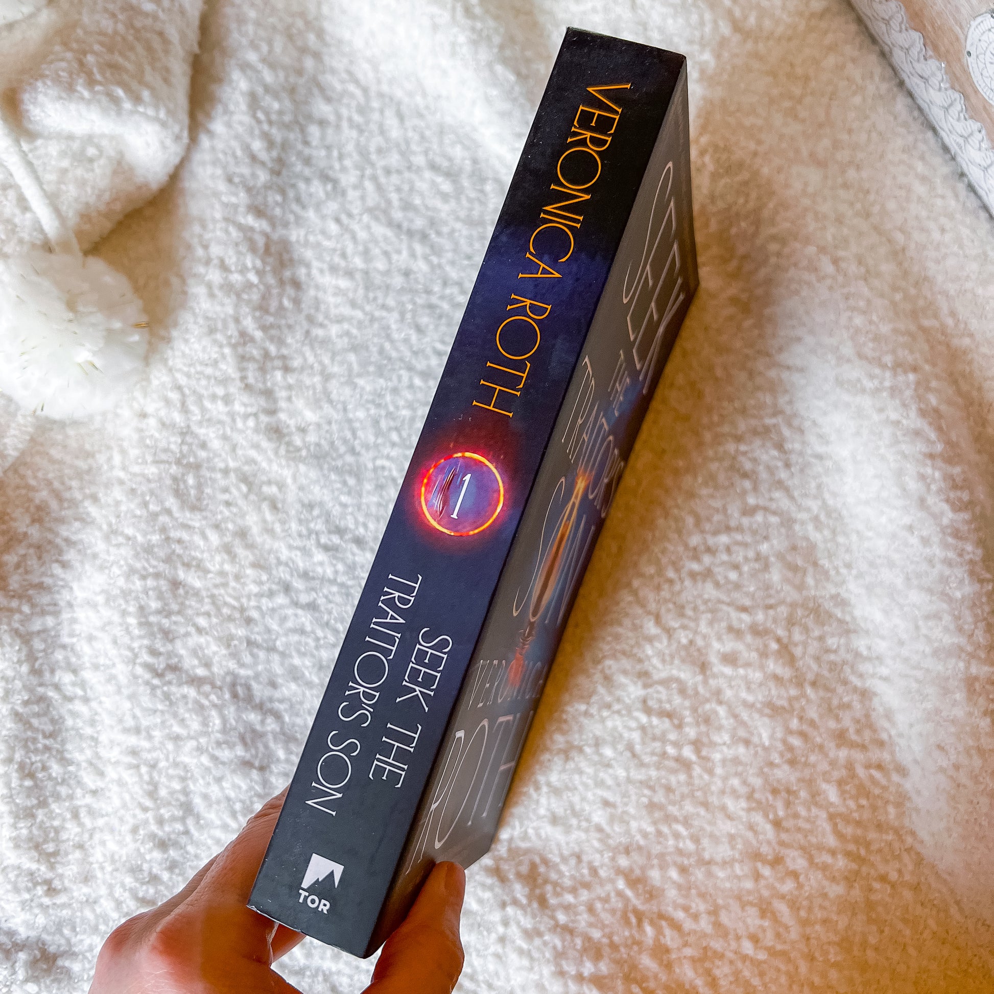 Book titled 'Seek the Traitor's Son' by Veronica Roth held against a soft white background