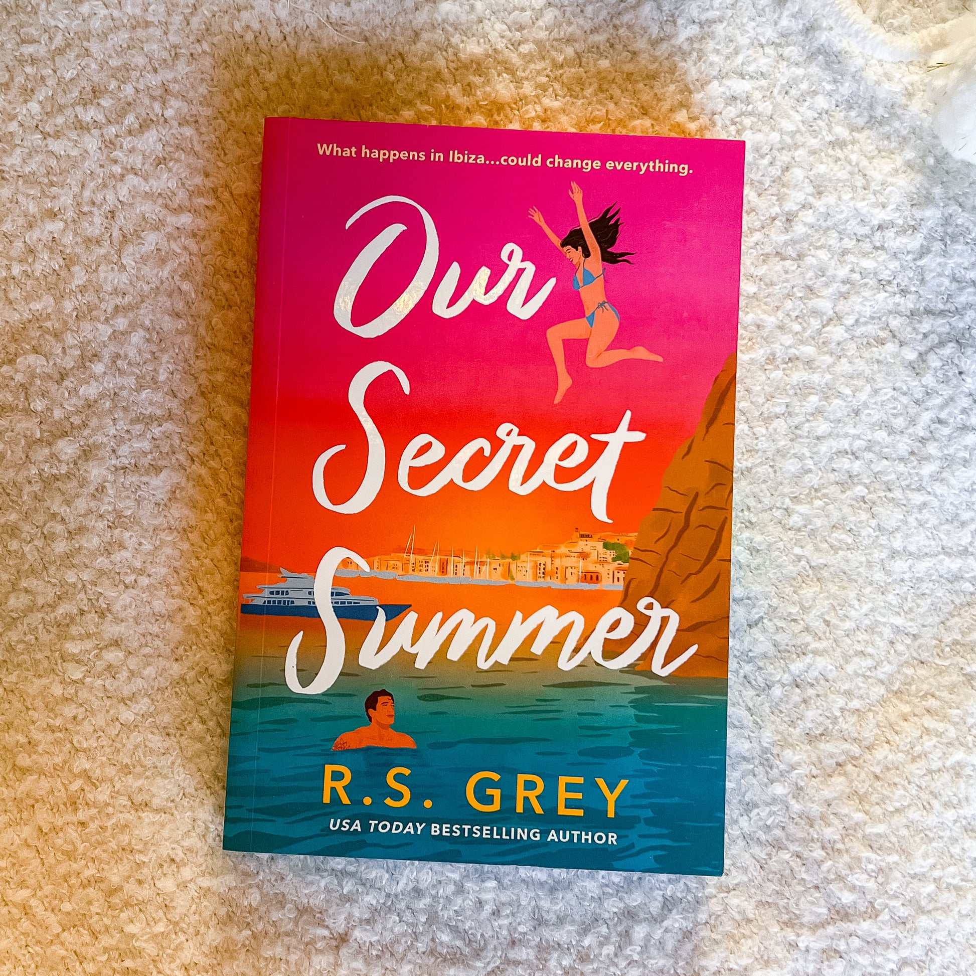 Book titled 'Our Secret Summer' by R.S. Grey on a textured surface