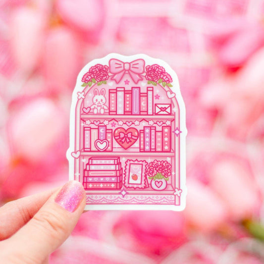Pink illustration of a bookshelf with decorative elements held against a pink blurred background